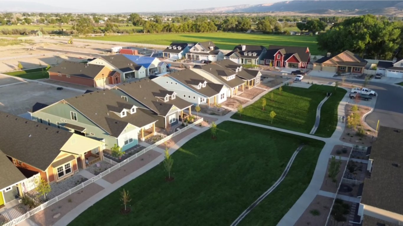 Aerial drone view of the Copper Creek neighborhood showing colorful houses, lush green parks, and sidewalks for daily walks, highlighting community lifestyle and outdoor living