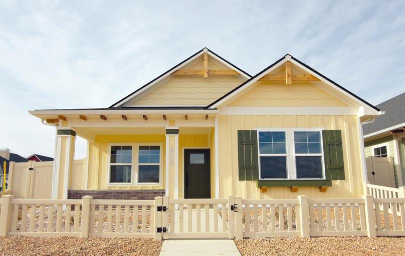 Charming yellow house exterior with a sidewalk leading to the front door and  windows that provide an unobstructed view of the park. 